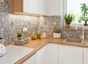 Bright Scandinavian kitchen corner with patterned tile backsplash, wooden countertop, white cabinets, and indoor plants