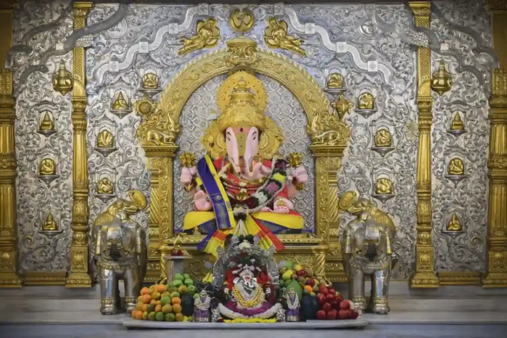 Ganesh idol with traditional temple decor and silver backdrop
