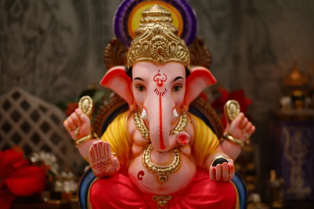 Statue of Lord Ganesha with detailed crown, traditional ornaments, and vibrant colors in a devotional setting